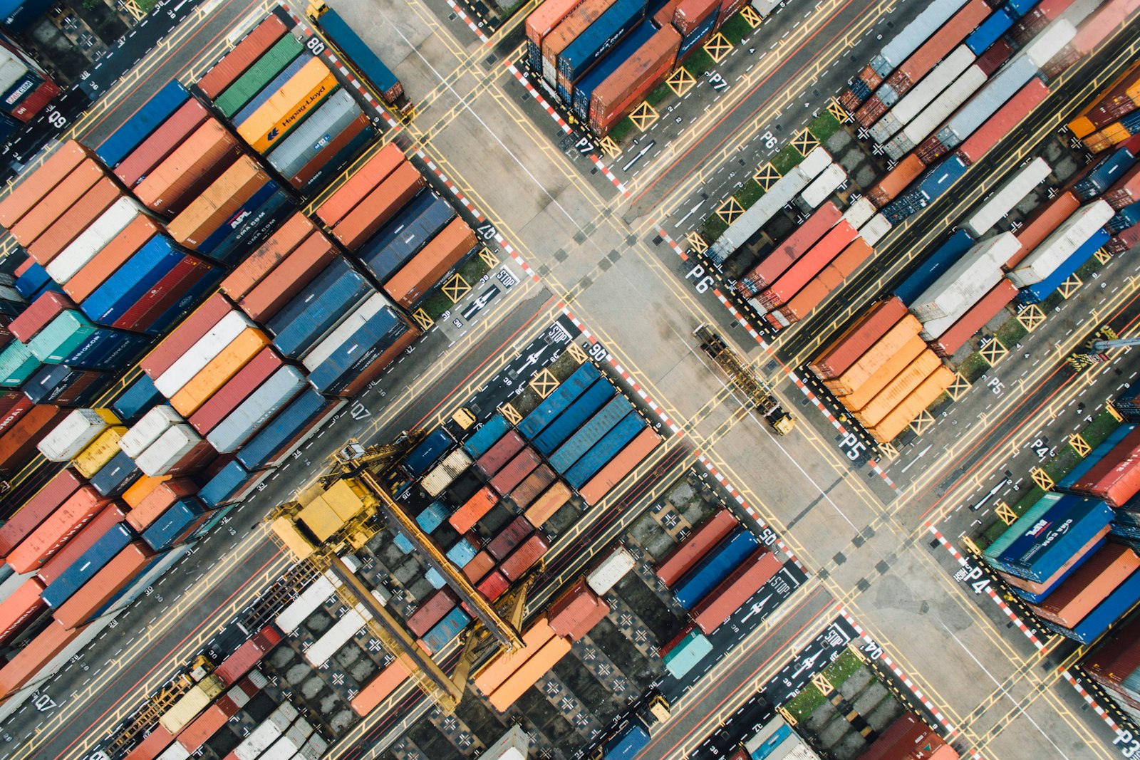 Stacked shipping containers at a busy port yard